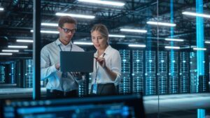 Man and woman working on a laptop in a server room