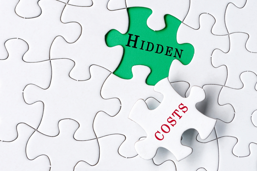 White Jigsaw Puzzle With Word Hidden Costs Over Green Background.