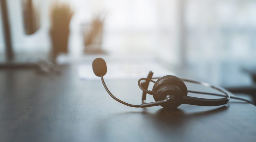 VOIP headset of customer support phone operator at workplace on desk.