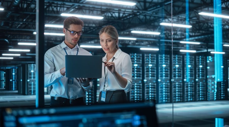 Man and woman working on a laptop in a server room